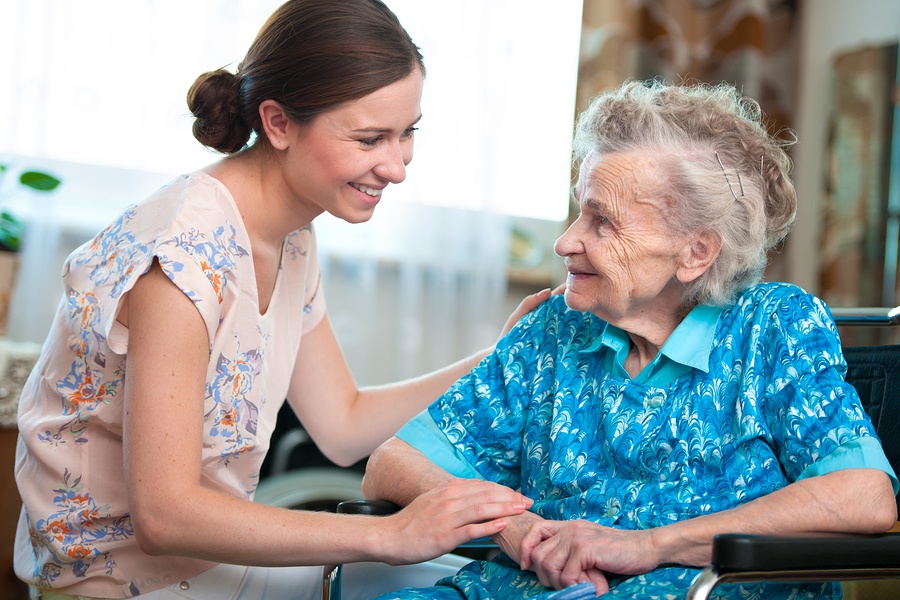 An elderly woman smiles kindly at her caregiver