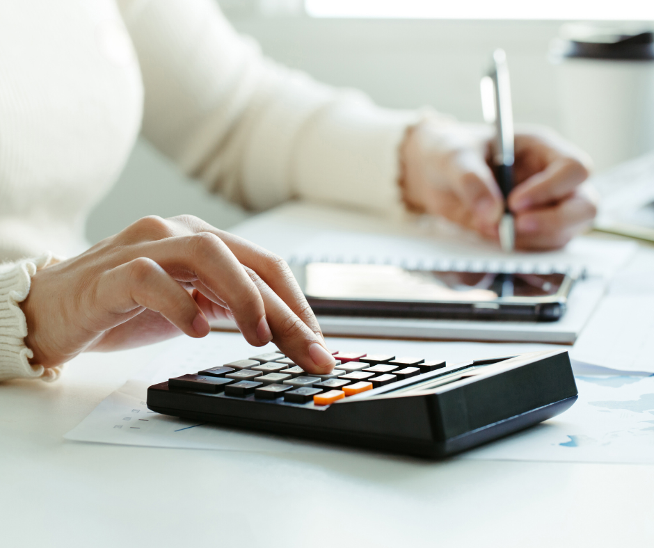 Person working at a desk while using a calculator and pen