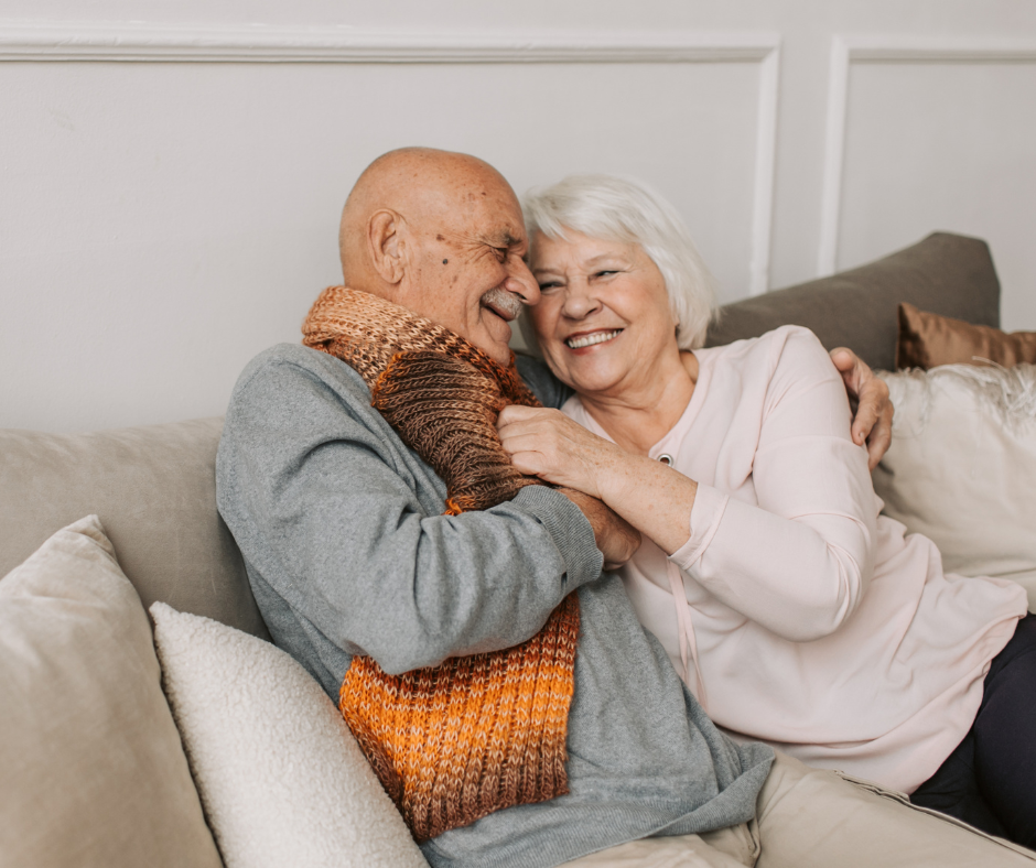 Older couple hugging each other while sat on a couch