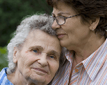 Two older women embrace each other