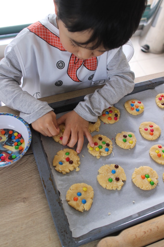 Young child with special needs putting cookie dough on baking sheet.
