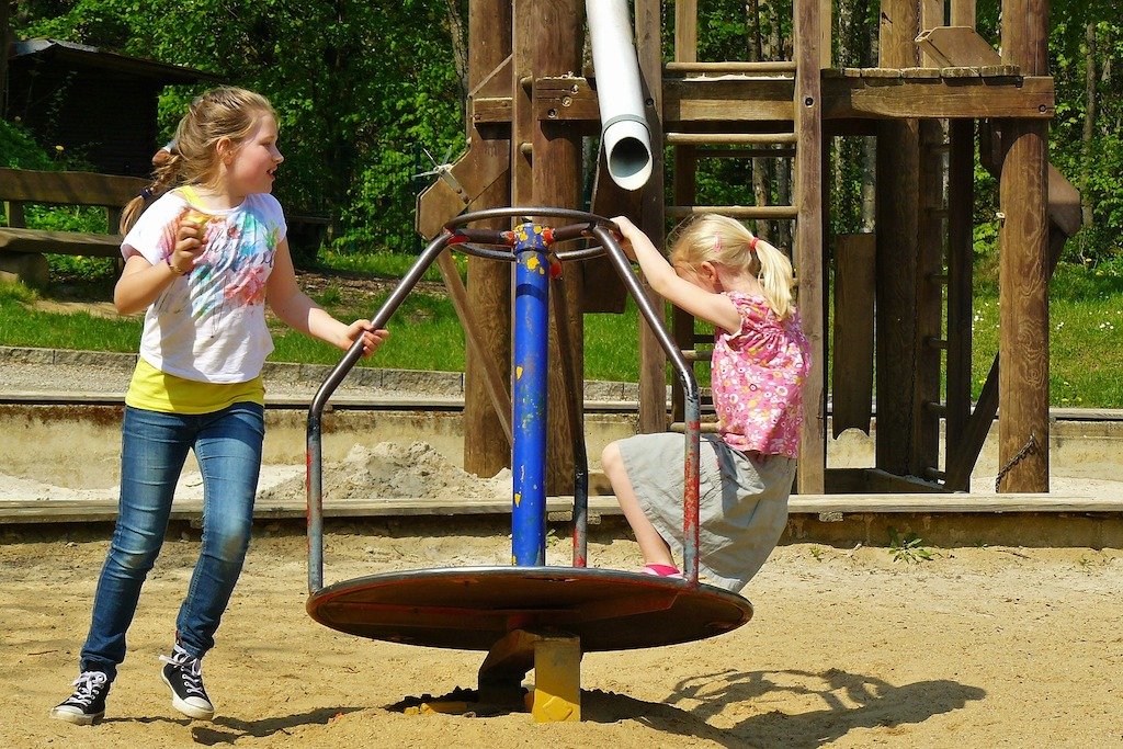 Two kids playing on a spinning playground toy