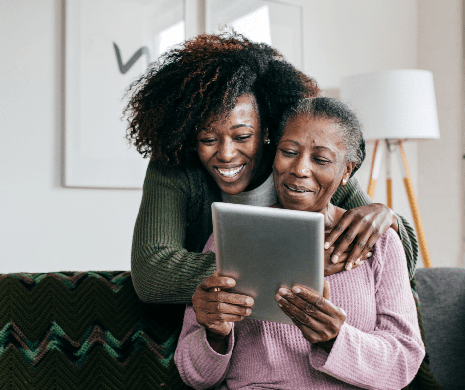 A mother and daughter smile while looking at a tablet