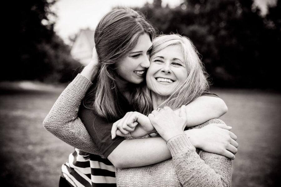 Daughter surprises mother with a loving hug from behind black and white