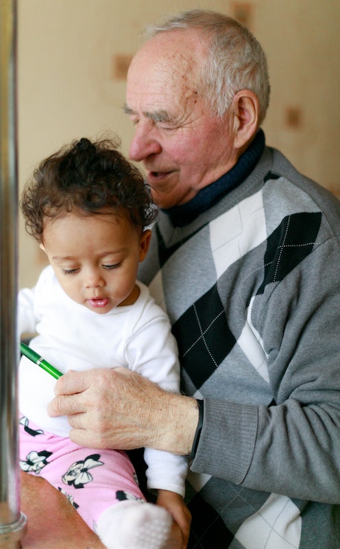 A senior man holds his granddaughter