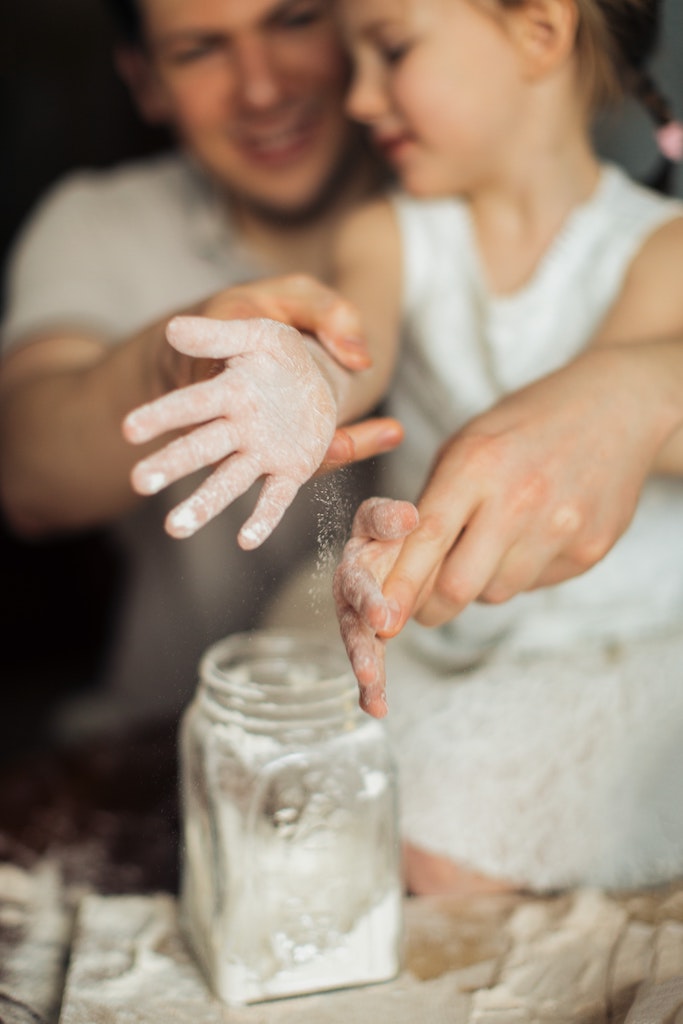 Father and daughter putting flour on their hands before baking.