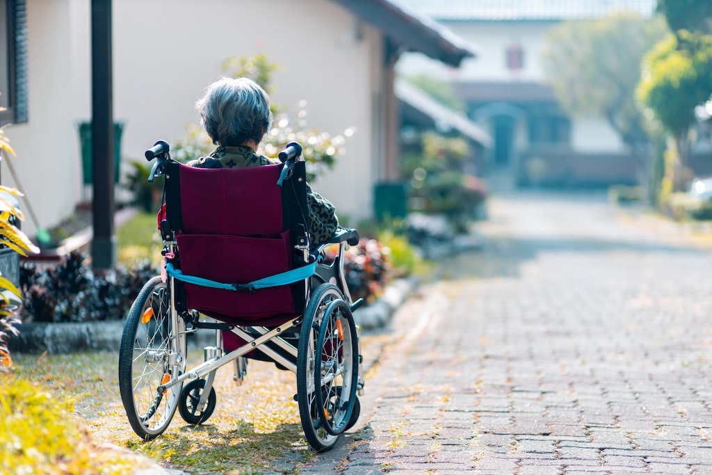 A woman in a wheelchair sits near a walking path