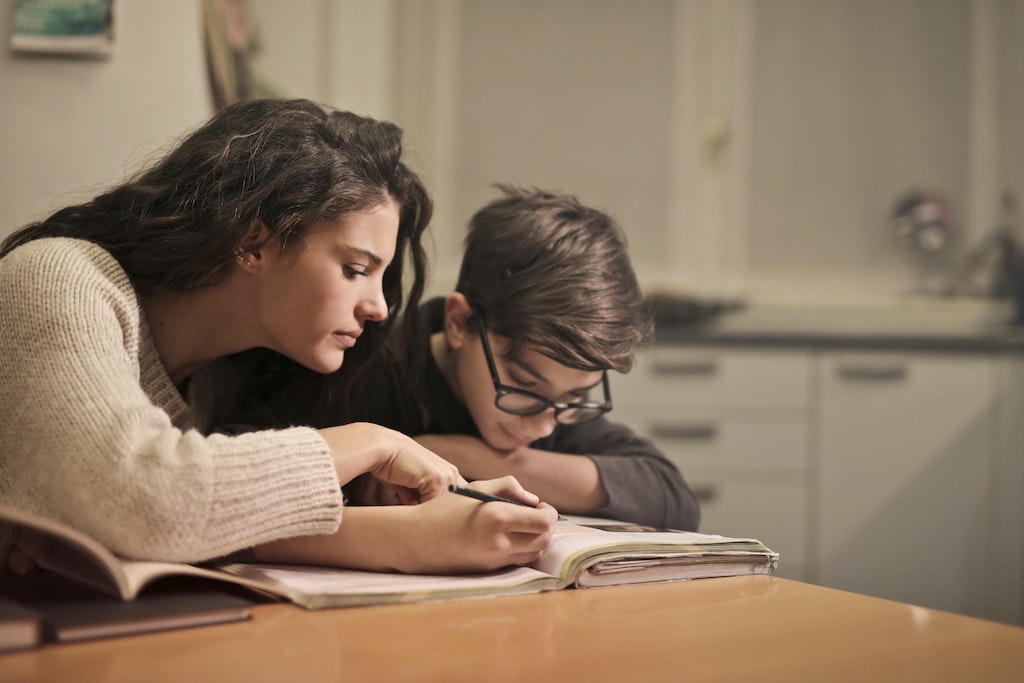 A home care worker helps a kid with his homework