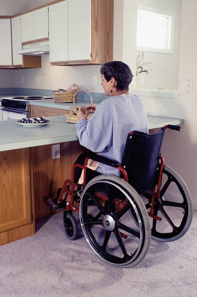 A woman in a wheelchair sitting at a kitchen counter