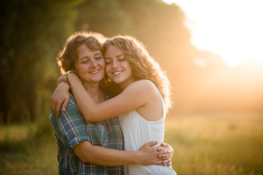 A mother and daughter hug in a field