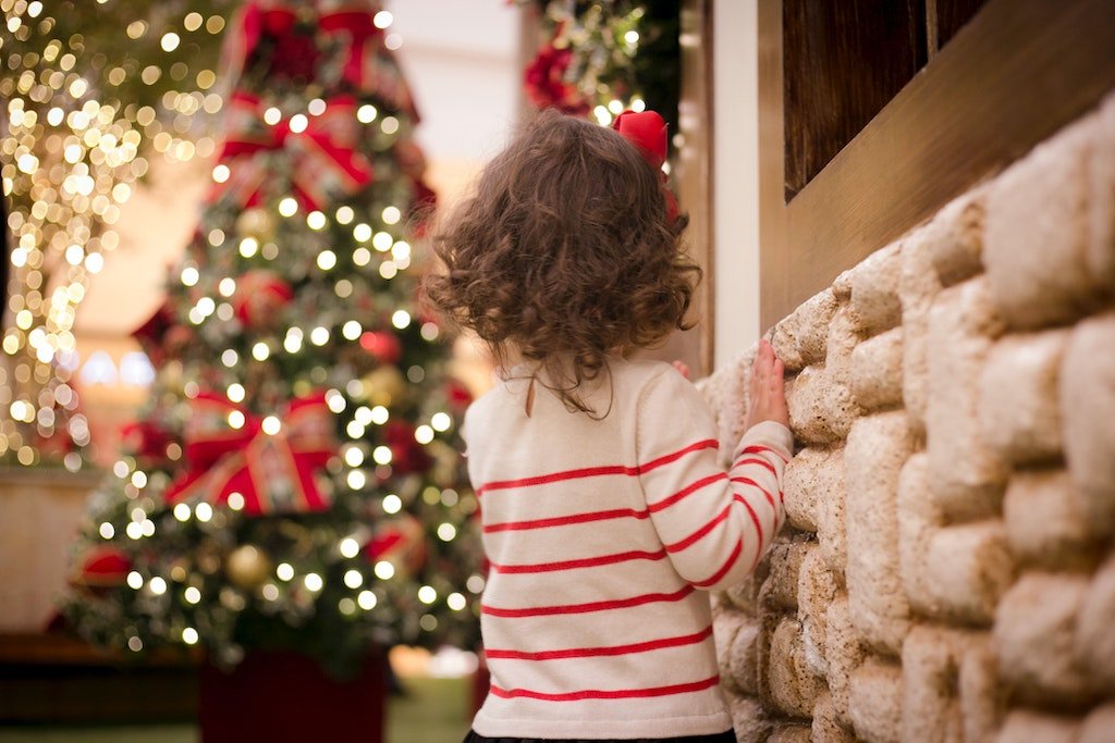 A child looks in awe at a lit Christmas tree