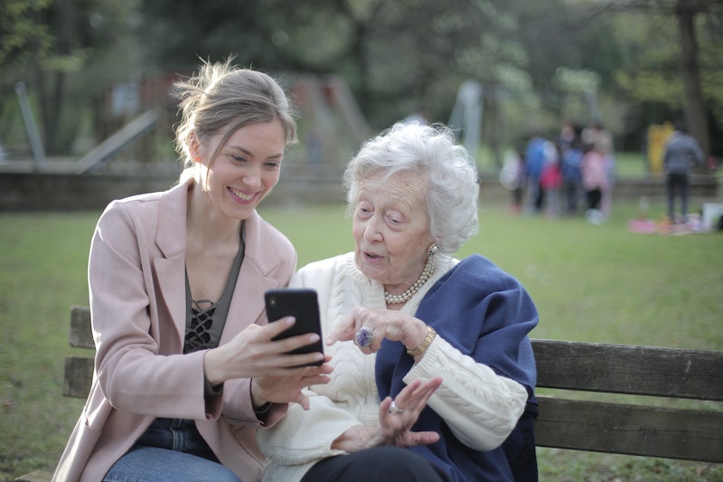 Two women sitting on a bench while looking at a phone together