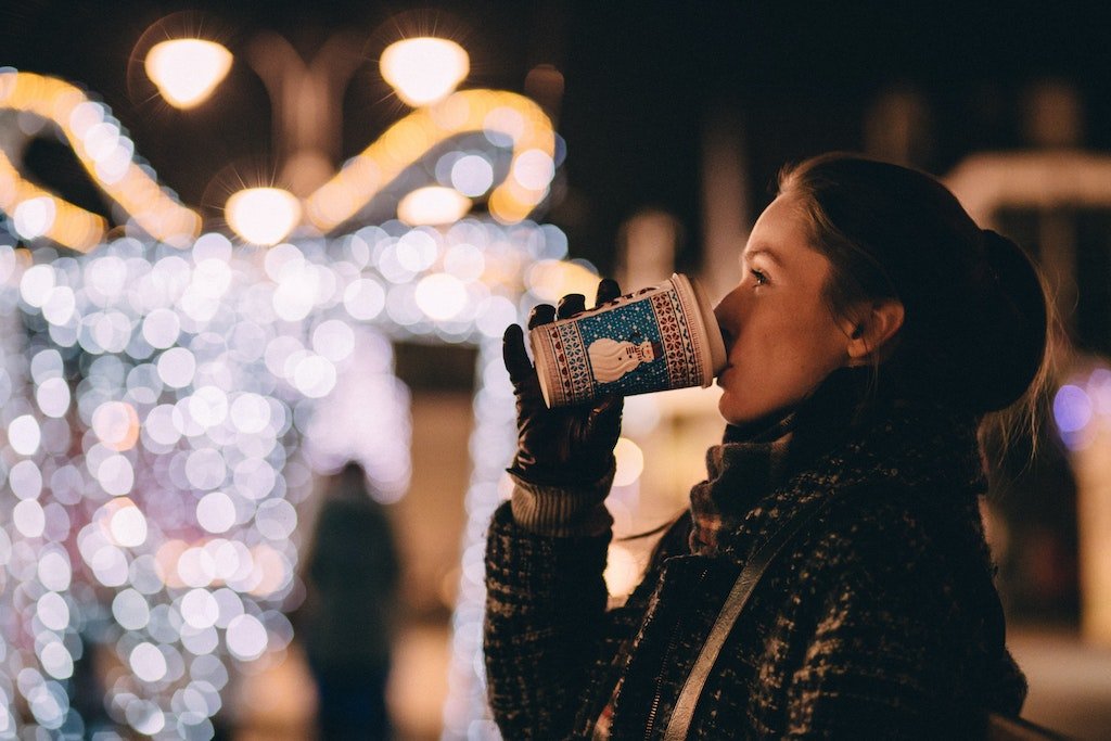 A woman drinks a winter themed cup of coffee