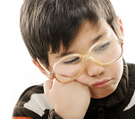 A young boy wearing glasses while looking frustrated