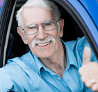 A senior man giving a thumbs up out a car window