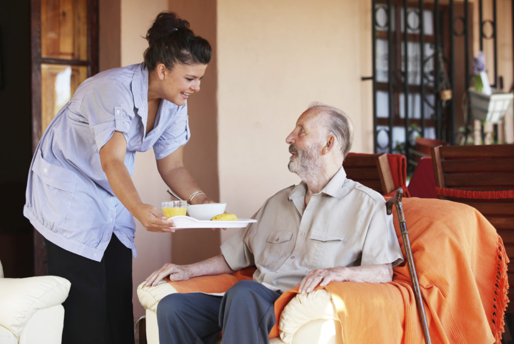 A caregiver delivers a meal to her client