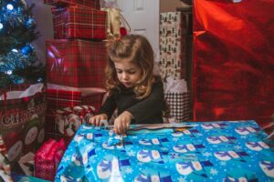 Young child living with autism opening a wrapped Christmas gift