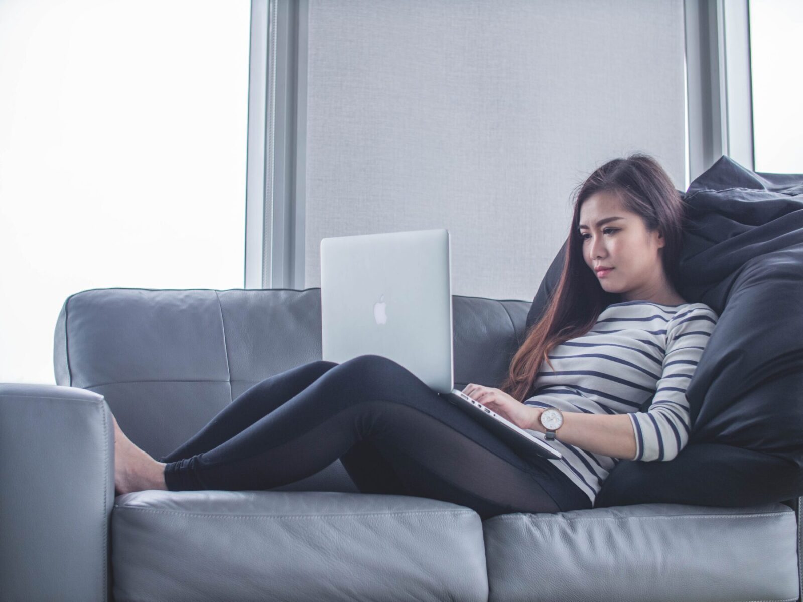 A woman using a laptop while on a couch
