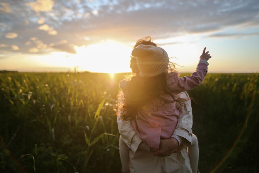 A mother carries her daughter near a corn field