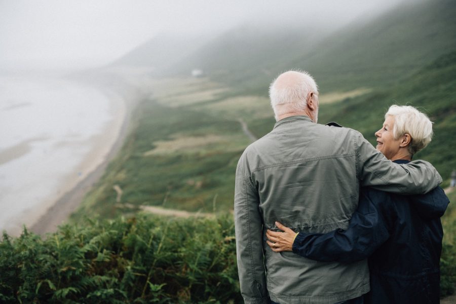A senior couple looks over the ocean from a hilltop