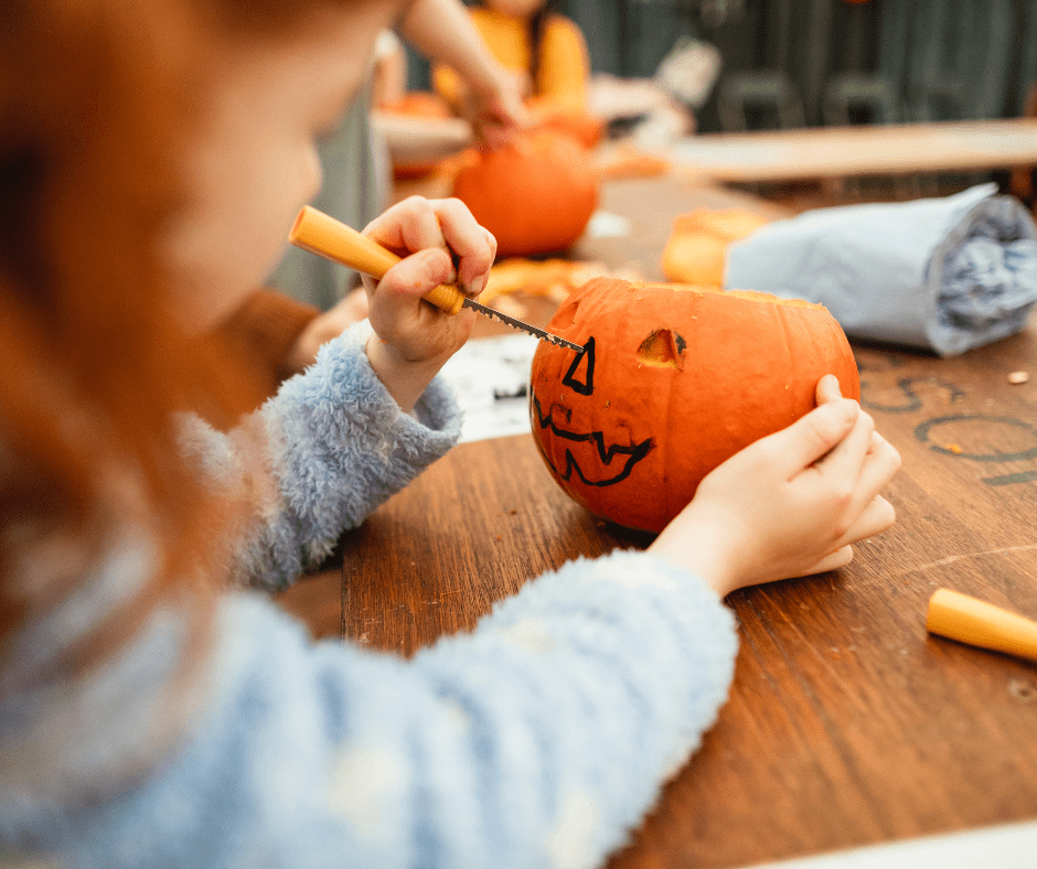 A child works on carving a pumpkin