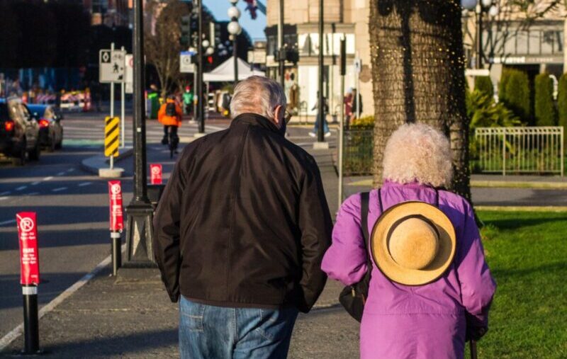 An old couple walks down city streets together