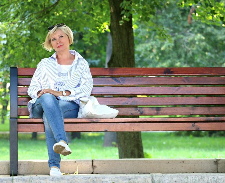 A woman looks up in thought while on a city bench
