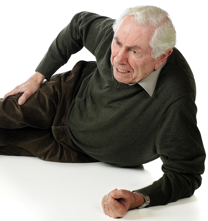 An older man laying on his side while holding his leg in pain