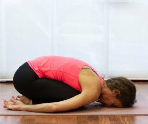 Family caregiver holding child's pose during yoga session.