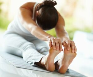 Woman holding forward stretch on yoga mat.