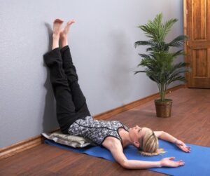 Young woman holding wall stretch pose in yoga studio.