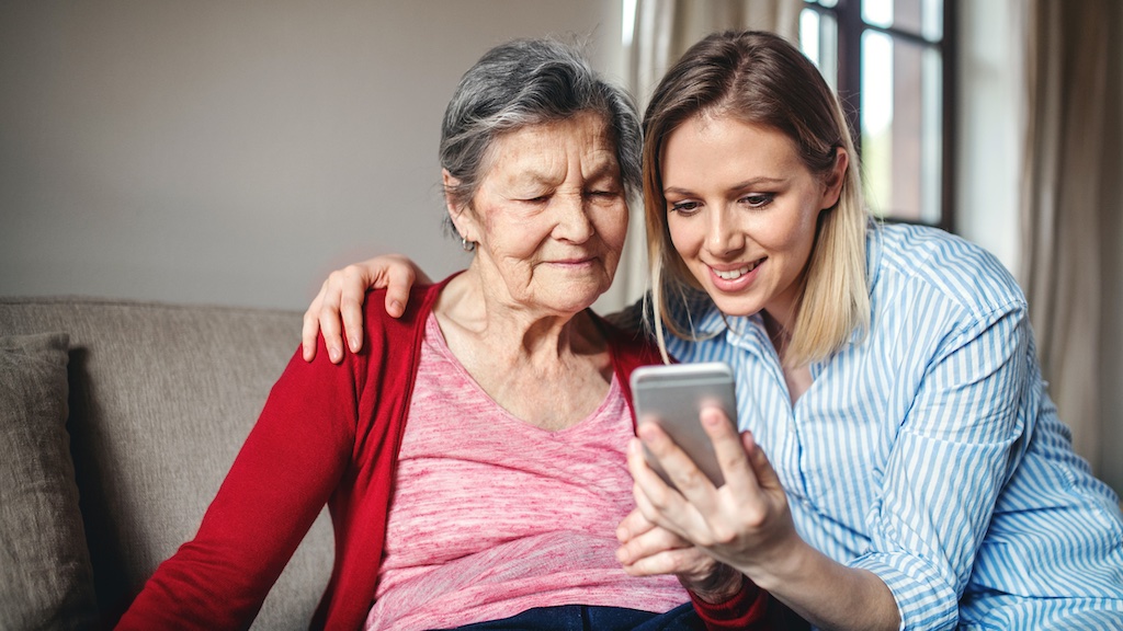 Young caregiver taking selfie with elderly woman.