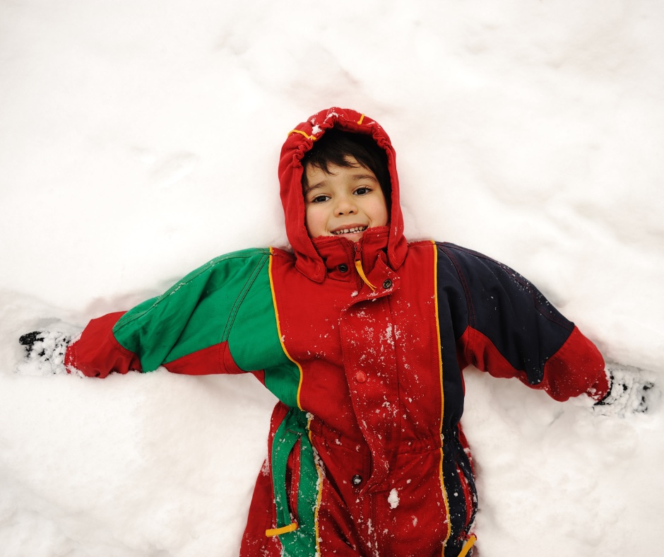 Young child wrapped in snow gear to play outside in snow.