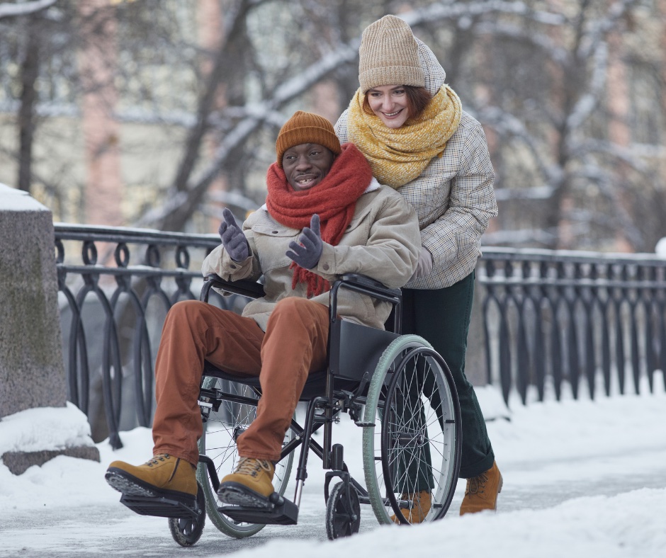 Caregiver pushing wheelchair in snow.