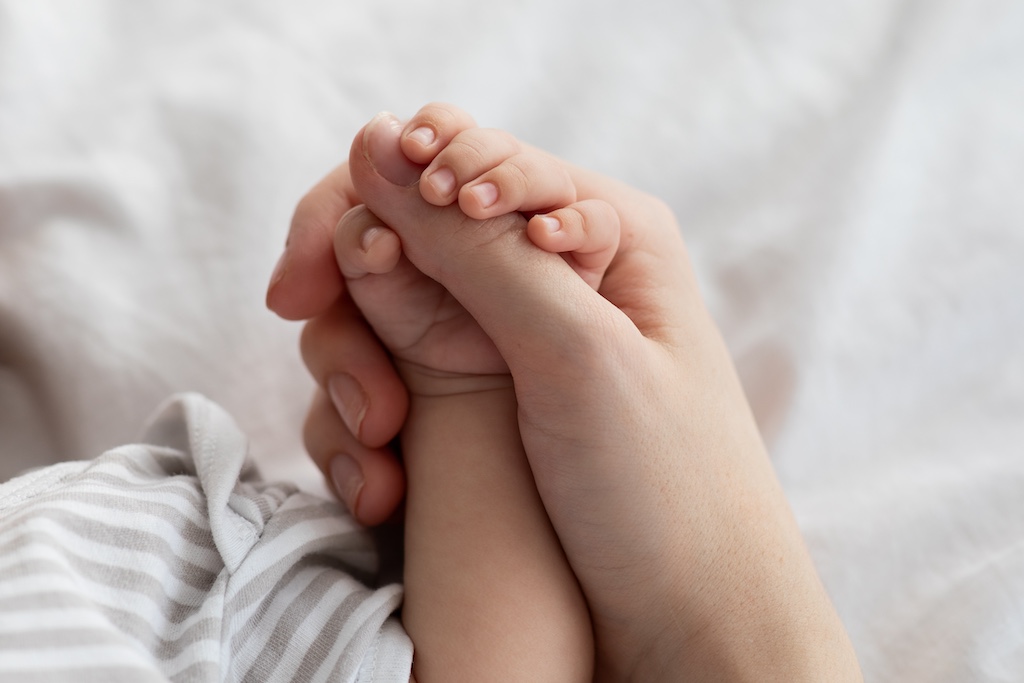 Caregiver holding infants hand.