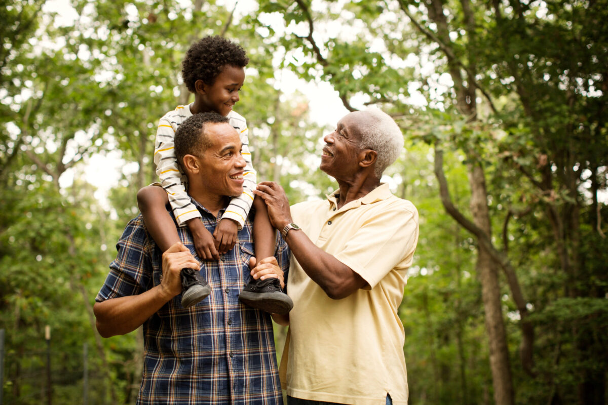 boy, father, and grandfather in forest smiling